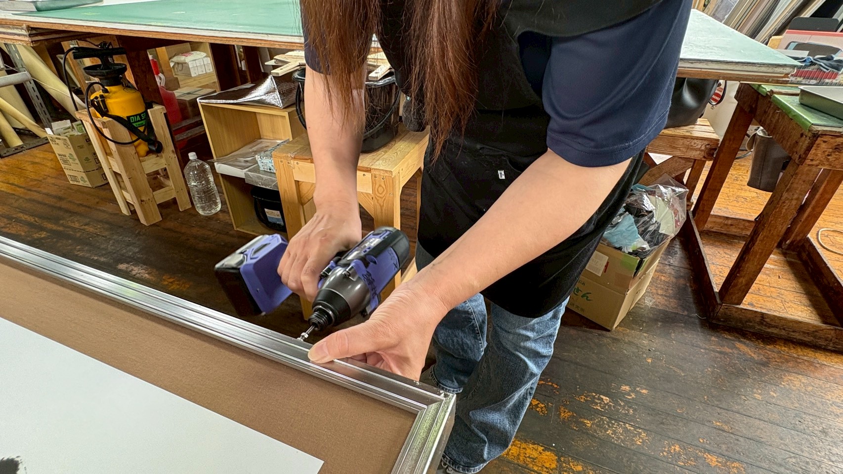額装作業の仕上げとして、ドライバーを使い慎重に裏板のねじを締める