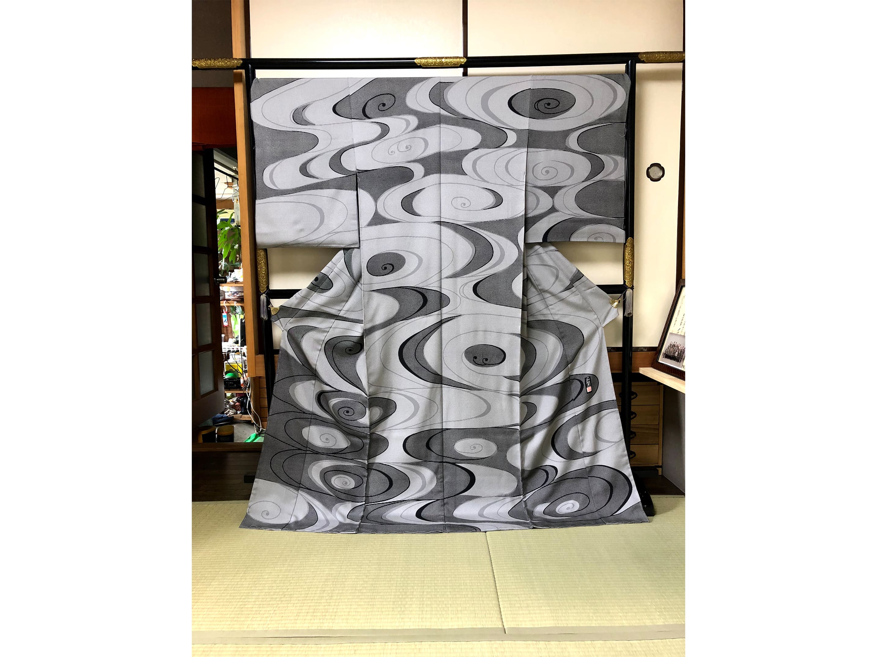 染小紋ならではの繊細な型染めで、蝶と流水模様が精巧に染め抜かれたえんじ色の反物 