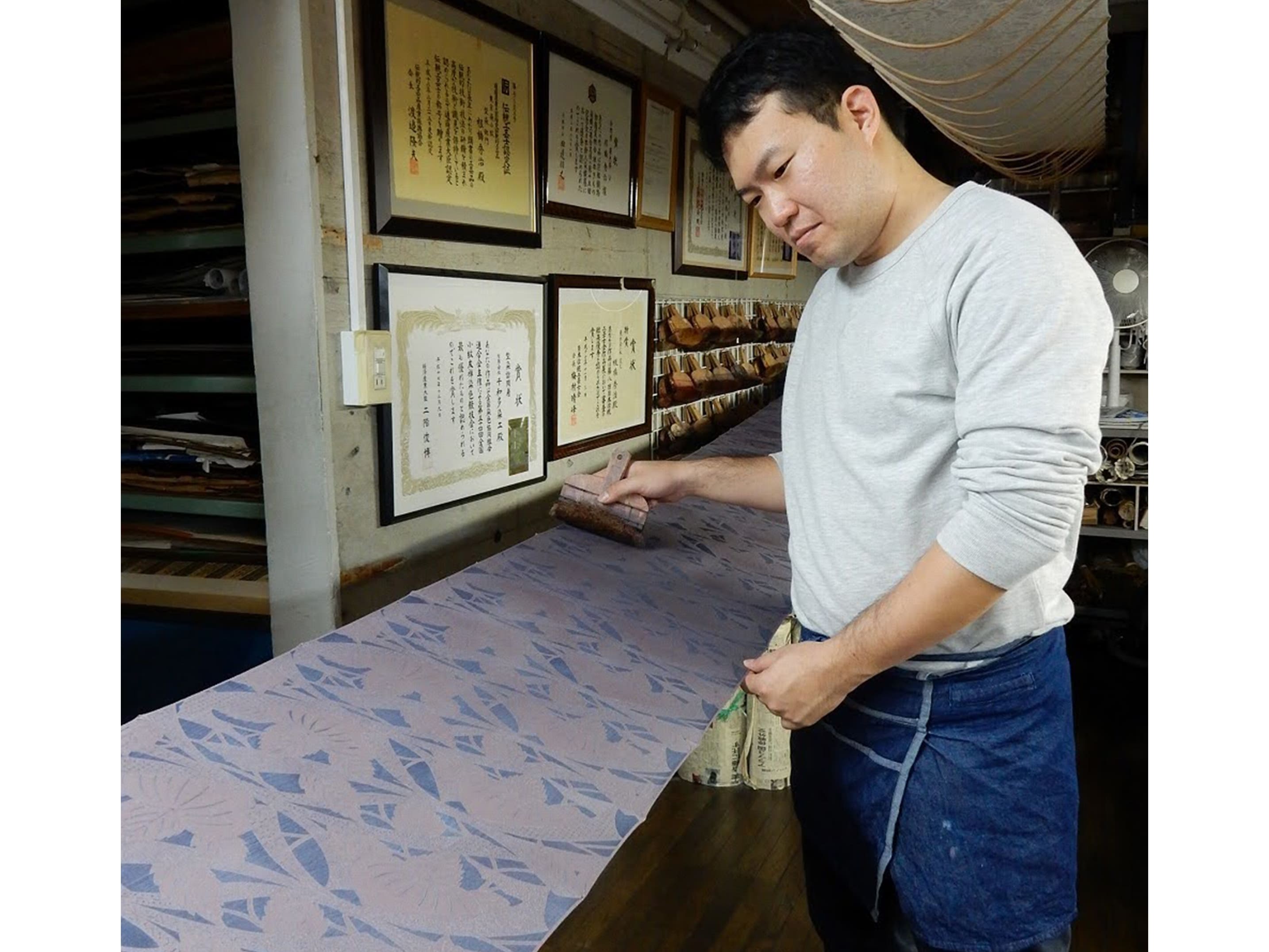 染小紋ならではの繊細な型染めで、蝶と流水模様が精巧に染め抜かれた青緑色の反物